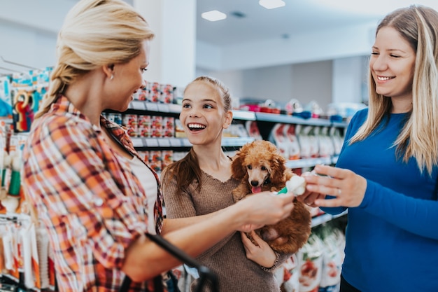 Mother and daughter with their poodle puppy in pet shop.