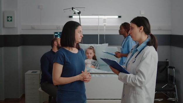 Mother discussing medical treatment with pediatrician doctor during disease examination