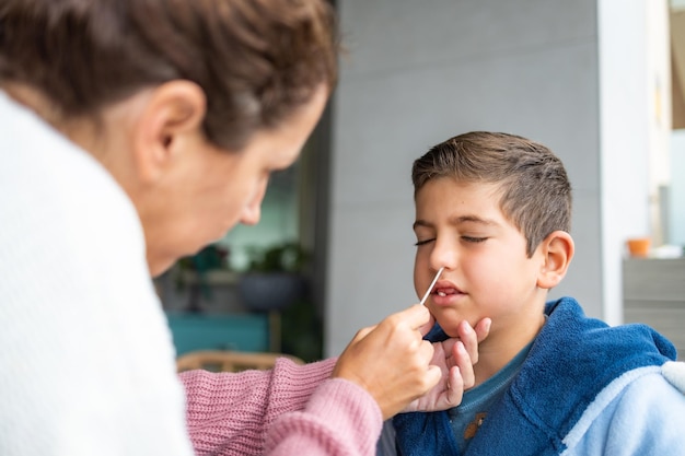 Photo mother doing an antigen test to her son at home