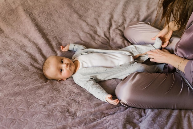 Mother dresses cute little baby boy in a jumpsuit Happy motherhood