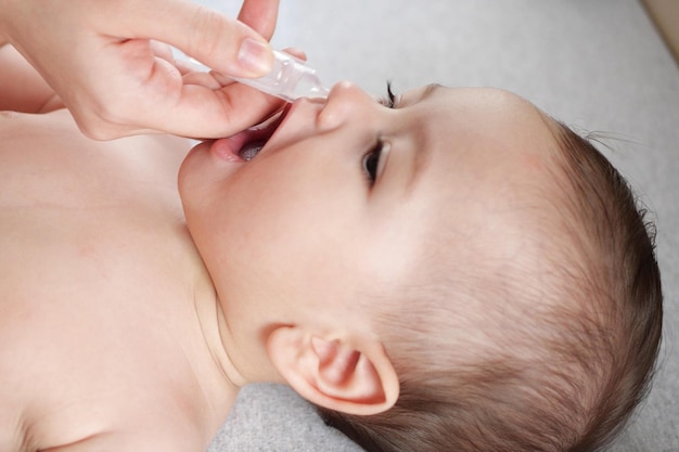 Mother dripping nasal drops for her son Baby healthcare concept top view