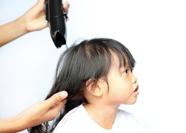 Mother drying hair of her child girl on white background