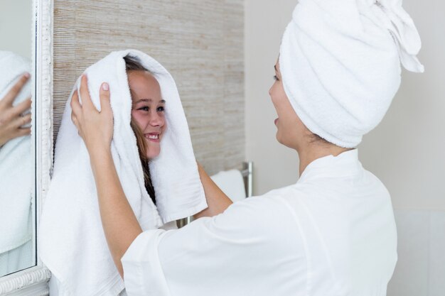 Madre che asciuga i capelli delle sue figlie con un asciugamano