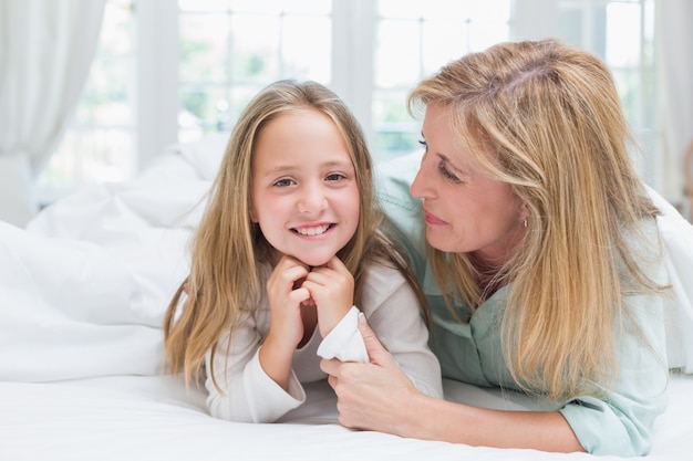 Madre che abbraccia sua figlia nel letto