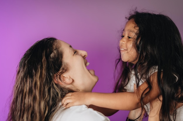 Photo mother embracing with cute girl against colored background