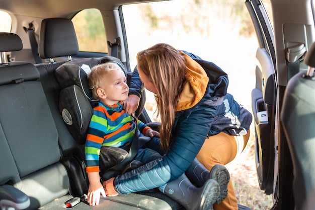 Foto madre che allaccia la cintura di sicurezza per il suo bambino nel suo seggiolino per auto. sicurezza del seggiolino auto per bambini