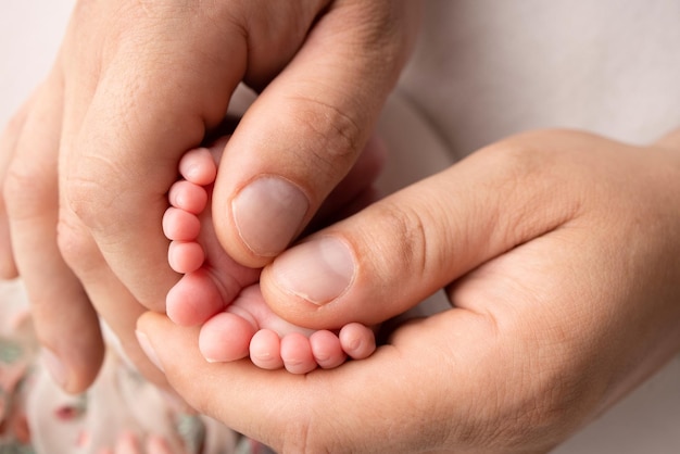 Mother and father are doing massage on her baby foot closeup\
baby feet in mother hands prevention of flat feet development\
muscle tone dysplasia family love care and health concepts