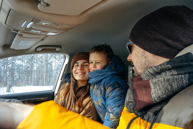 Мать, отец и ребенок, путешествующие на машине в отпуск в горы зимой