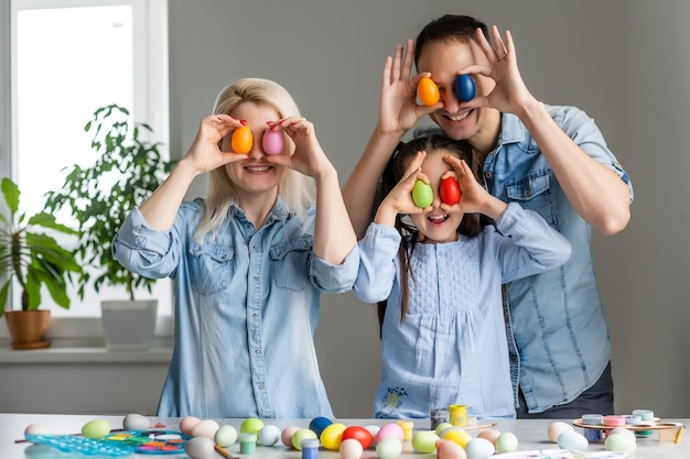 Mother, father and daughter are painting eggs. Happy family are preparing for Easter.