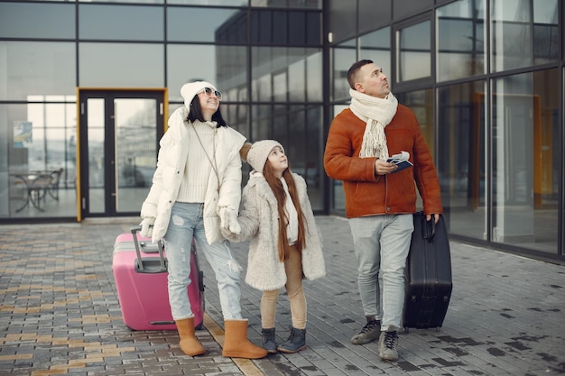 Mother father and daughter with luggage going from airport terminal