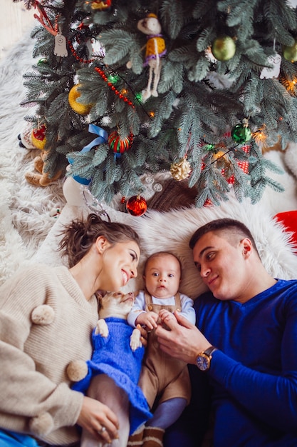 The mother,father,dog and baby lie on the floor  near Christmas Tree