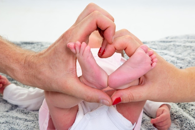 Mother father Holding Baby Feet In Heart Shaped Hand in newborn Infant Care Concept