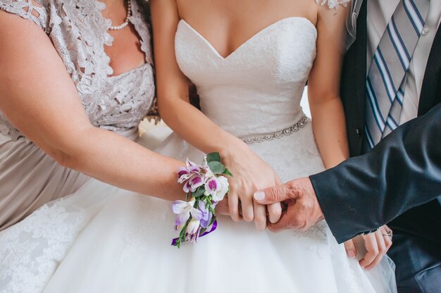 Mother and father holding hands of his daughter - young bride at her wedding day. Wedding family.