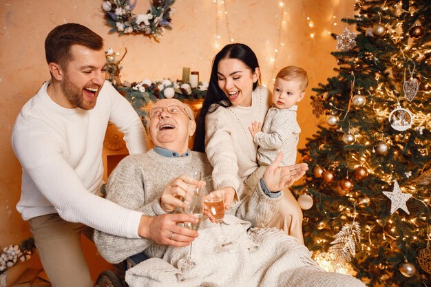 Mother father little son and old grandfather on a wheelchair sitting near Christmas tree