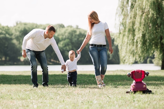 Mamma, papà e giocano con il loro figlioletto a fare una passeggiata nel parco estivo