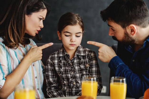 Mother and father scolding their daughter They pointing fingers at her