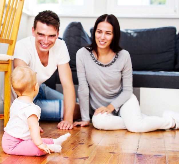 Photo mother and father sitting with baby on floor at home