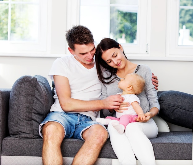 Mother and father sitting with baby on sofa at home