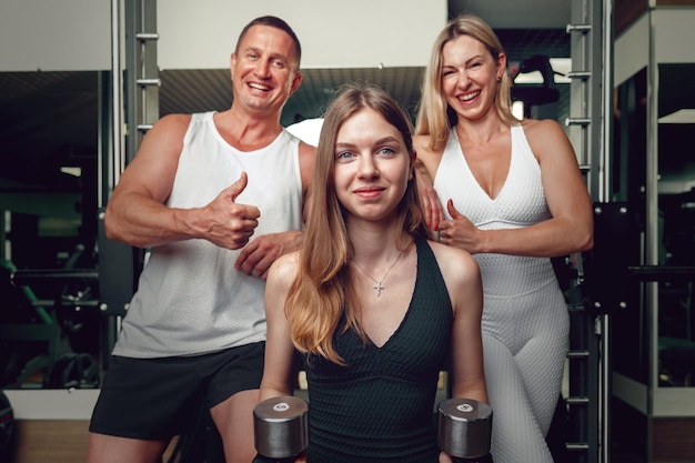 Mother father and teen daughter training together in a gym