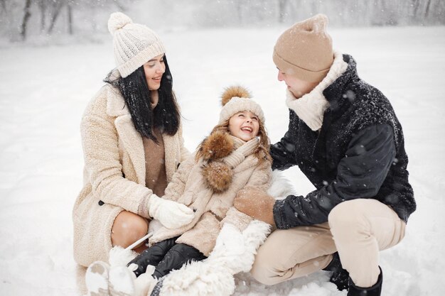 Mother father and their little daughter playing outdoors at winter day