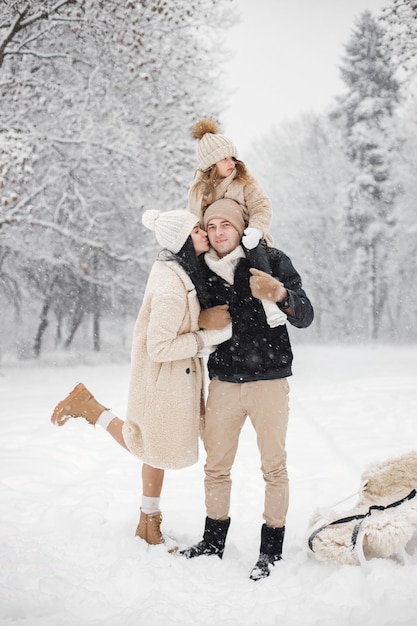 Mother father and their little daughter playing outdoors at winter day