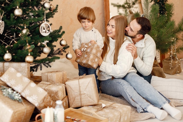 Mother father and their son sitting near Christmas tree at home