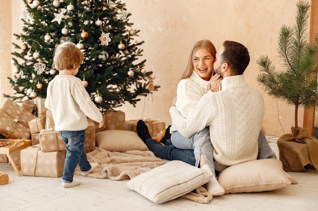 Mother father and their son sitting near Christmas tree at home