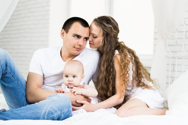 Foto madre e padre con piccolo bambino in un letto