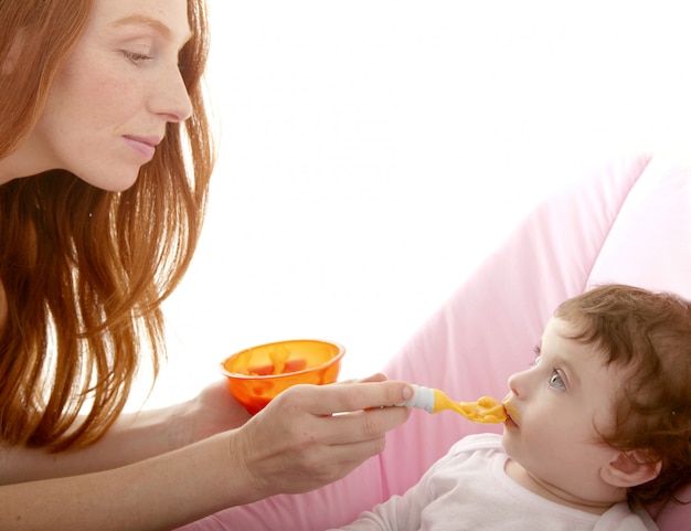 Mother feeding baby yellow spoon