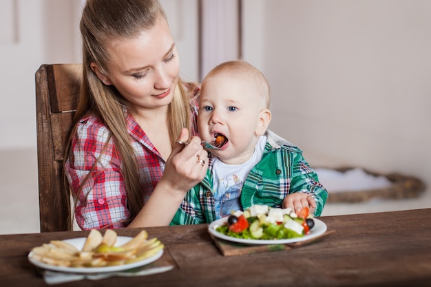 母親が子供を養っている。幼い子供のための最初の固形食品。