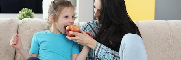 Mother feeding daughter with apple fruit add vitaminized product to eating