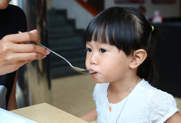 그녀의 아이 숟가락에 음식을 먹이 어머니.