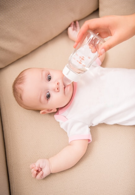 Mother feeding her adorable daughter from bottle.