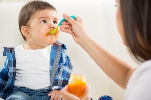 Mother feeding her baby boy with a spoon.