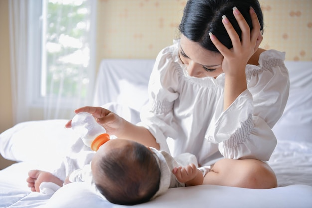 Mother feeding milk to son with bottle at home