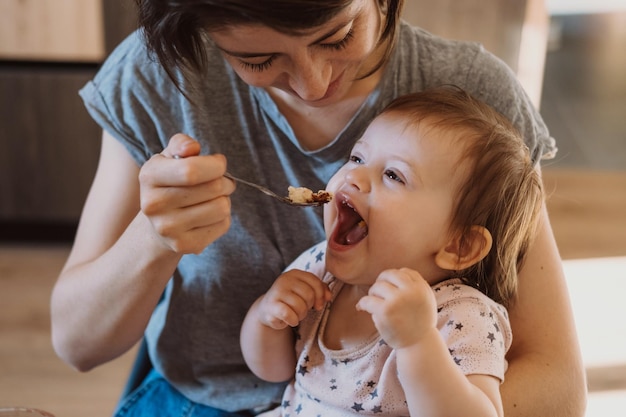 Madre che alimenta con il cucchiaio il suo piccolo bambino a casa sano ragazza cura del bambino cura della famiglia