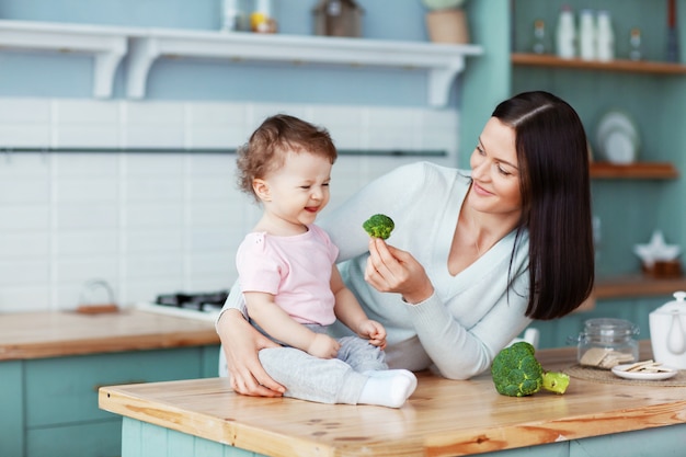 Мать кормит ребенка брокколи и овощами