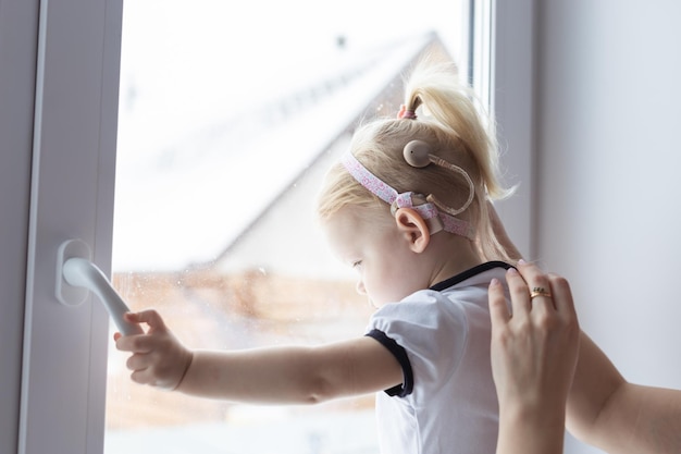 Foto madre che fissa l'impianto cocleare di sua figlia per la sordità e il concetto di diversità tecnologie innovative nel trattamento della sordità