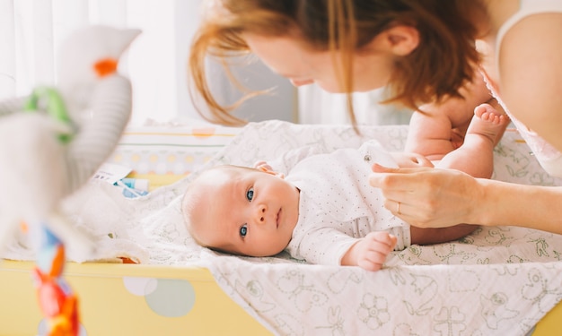 Mother gently care of baby on the changing table at home