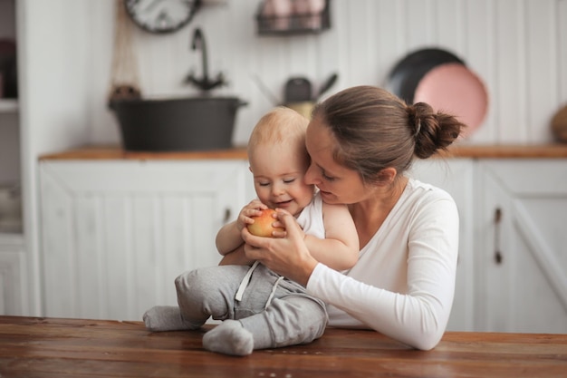 Мать дает ребенку яблоко мать обнимает своего сына настоящий интерьер яркая кухня