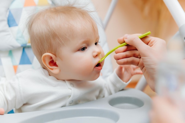 Mother gives fruit sauce to babymom feeds baby on highchairbaby food