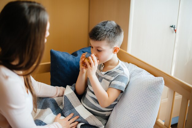 Photo mother gives hot tea with lemon to her baby during illness and virus. medicine and care.