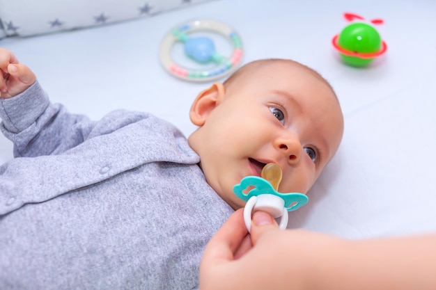 Mother gives pacifier to her newborn daughter. Selective focus