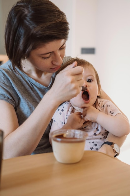 Mother giving food to her baby girl at home healthy food diet baby care family care