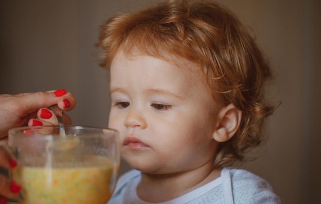 家で愛らしい子供に健康的な食べ物を与える母親は、子供たちに家族の食べ物を食べさせ、