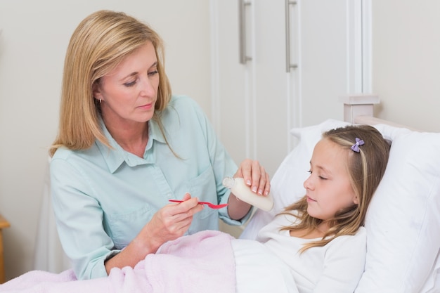 Photo mother giving her daughter cough medicine