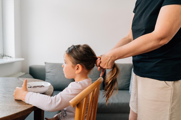 Mother to granny doing ponytail for little girl before school Lifestyle family moments