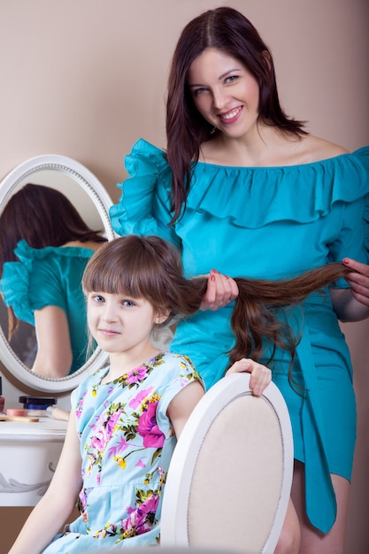 Mother hairdressing her preteen beautiful daughter at home.