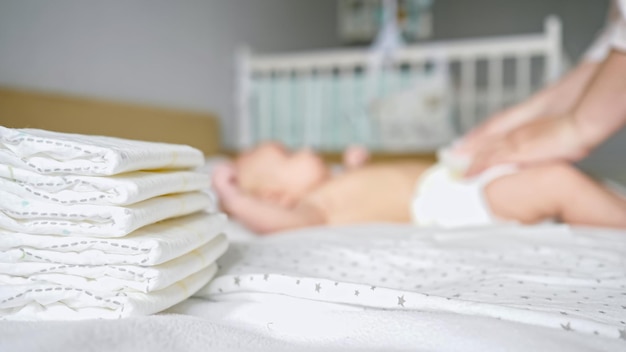 Mother hands dress baby in new diaper on blurred background