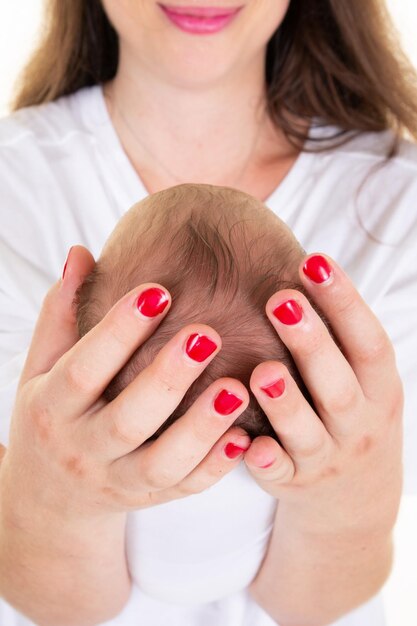 Mother hands holding little head with tiny hair of newborn baby